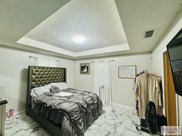 bedroom with a textured ceiling and a tray ceiling