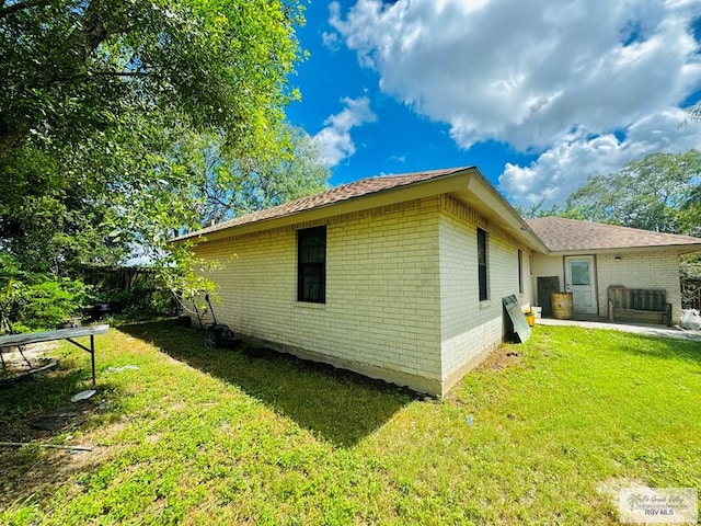 view of side of property featuring a lawn and a patio