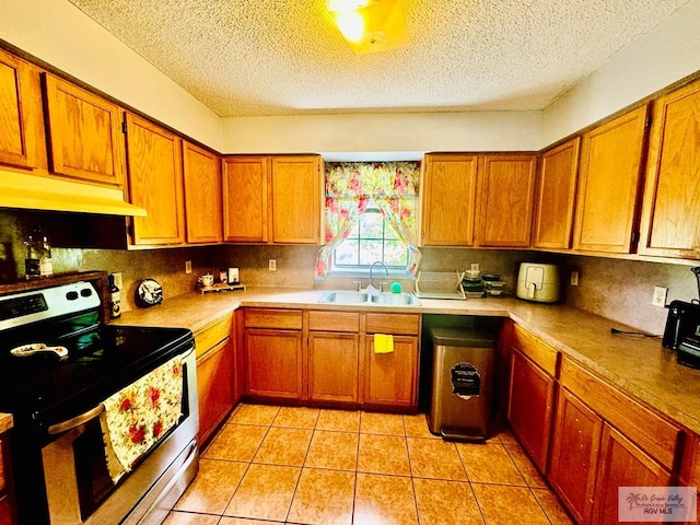 kitchen with stainless steel electric stove, sink, light tile patterned floors, and a textured ceiling