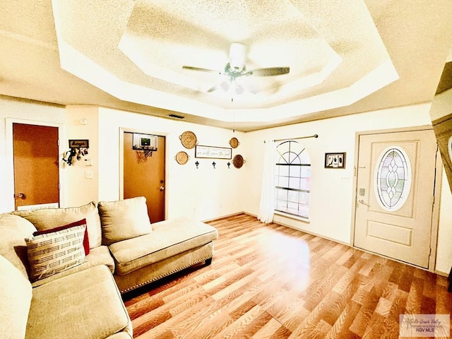 interior space with a tray ceiling, ceiling fan, a textured ceiling, and hardwood / wood-style flooring