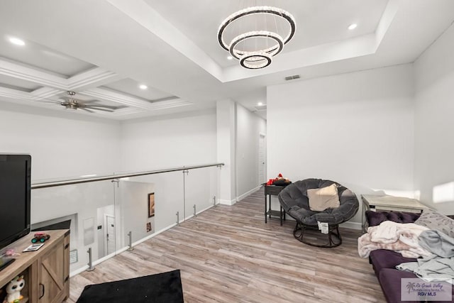 sitting room with light wood-type flooring, ceiling fan with notable chandelier, and coffered ceiling