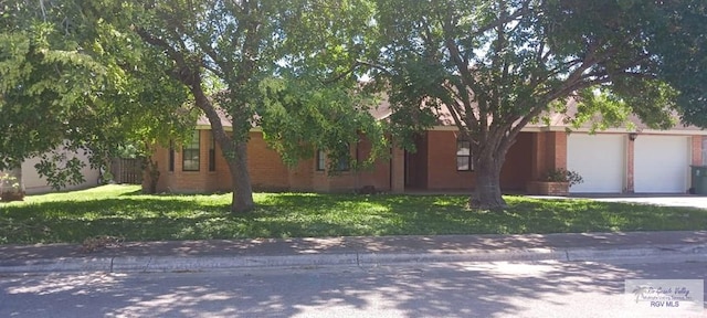 ranch-style home featuring an attached garage, concrete driveway, and a front lawn