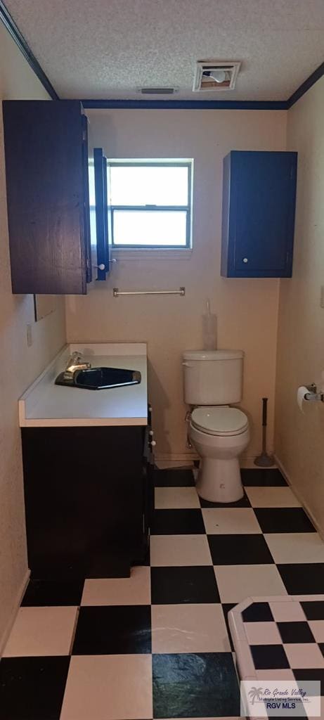 half bath featuring tile patterned floors, vanity, a textured ceiling, and toilet