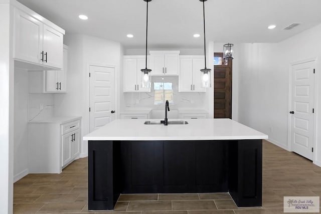 kitchen featuring a center island with sink, white cabinets, pendant lighting, and sink