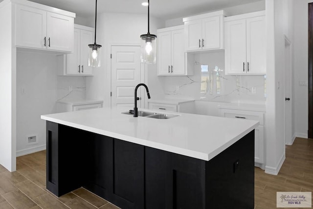 kitchen with a center island with sink, hanging light fixtures, and sink