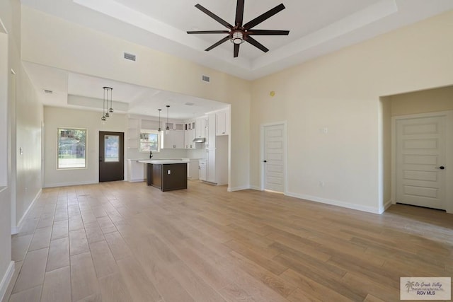 32773 Jorge St, Los Fresnos, TX 78566 - unfurnished living room featuring light wood-type flooring, a ceiling fan, baseboards, and a raised ceiling