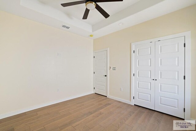 32773 Jorge St, Los Fresnos, TX 78566 - unfurnished bedroom featuring a raised ceiling, wood finished floors, visible vents, a closet, and baseboards