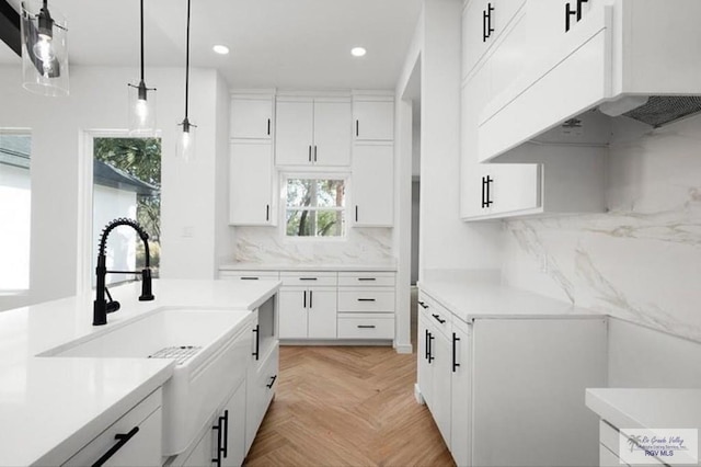 kitchen with extractor fan, white cabinets, light countertops, hanging light fixtures, and decorative backsplash