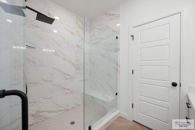 bathroom featuring a marble finish shower and vanity