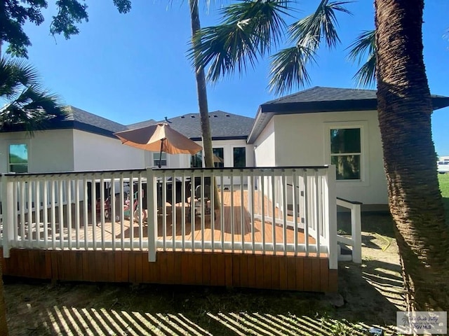 back of property with a deck and stucco siding