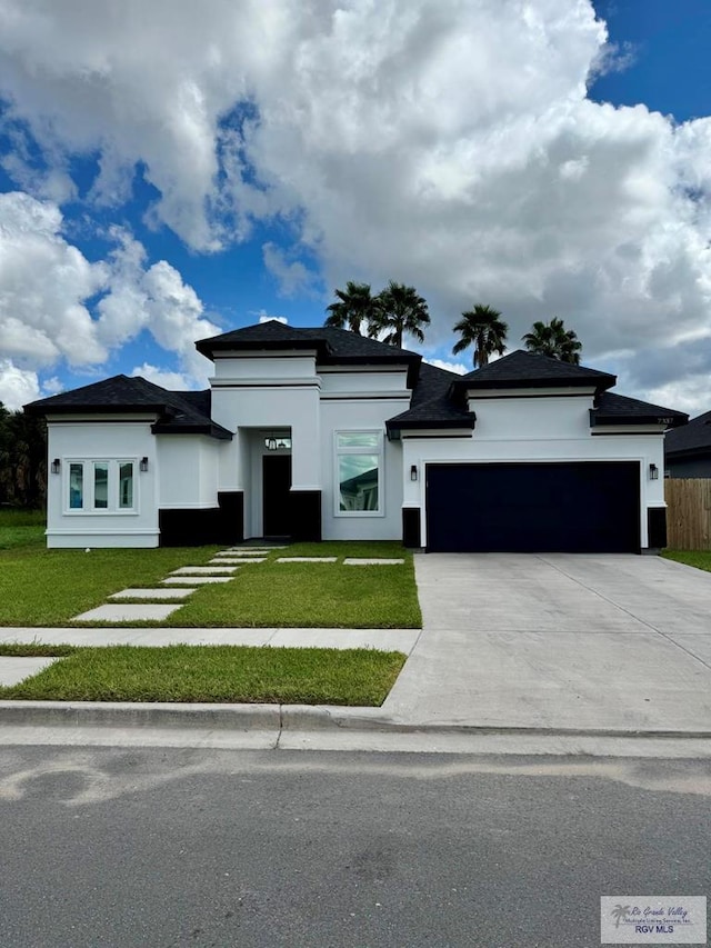 prairie-style house featuring an attached garage, driveway, a front lawn, and stucco siding