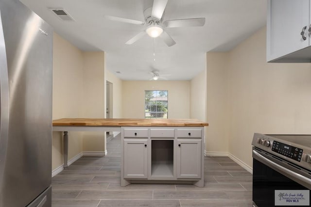 kitchen with ceiling fan, wood counters, light hardwood / wood-style floors, white cabinets, and appliances with stainless steel finishes