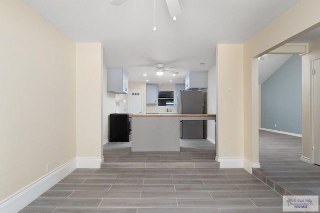 kitchen with hardwood / wood-style flooring, ceiling fan, white cabinetry, and stainless steel refrigerator