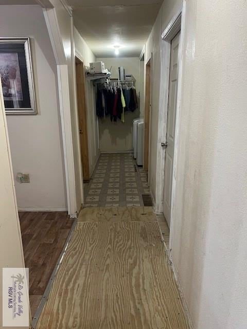 corridor with wood-type flooring and separate washer and dryer