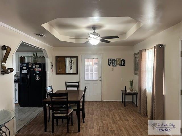 dining space featuring a raised ceiling, ceiling fan, and dark hardwood / wood-style flooring