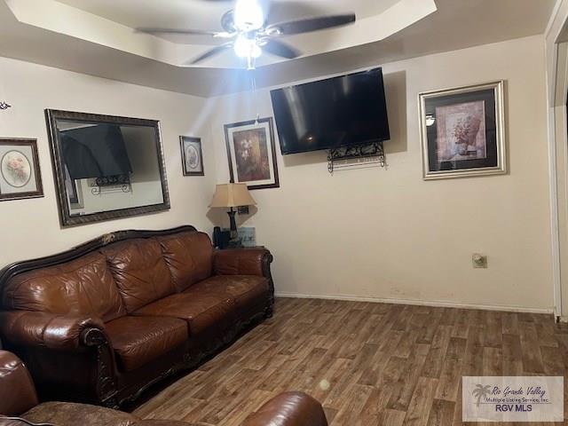 living room featuring a tray ceiling, hardwood / wood-style flooring, and ceiling fan