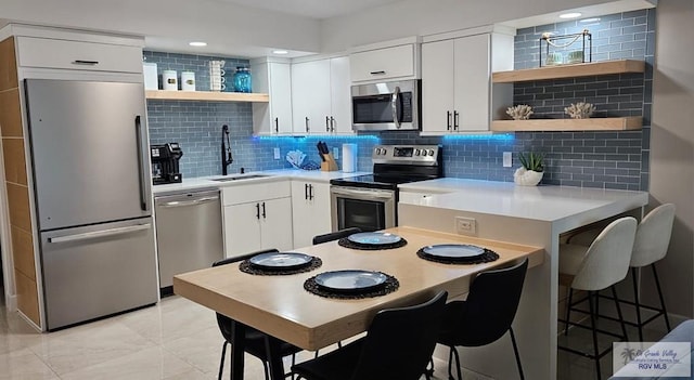 kitchen featuring decorative backsplash, white cabinetry, sink, and stainless steel appliances