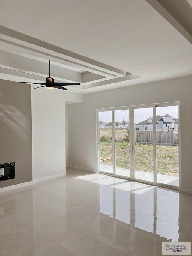 unfurnished living room featuring heating unit, ceiling fan, and a tray ceiling