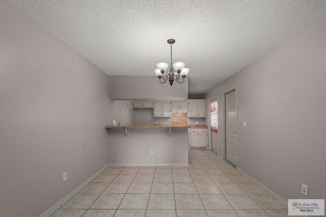 kitchen featuring decorative light fixtures, a breakfast bar area, light tile patterned floors, kitchen peninsula, and an inviting chandelier