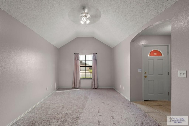 carpeted entrance foyer featuring ceiling fan, vaulted ceiling, and a textured ceiling