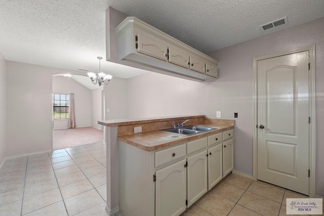 kitchen with pendant lighting, kitchen peninsula, sink, and light tile patterned floors