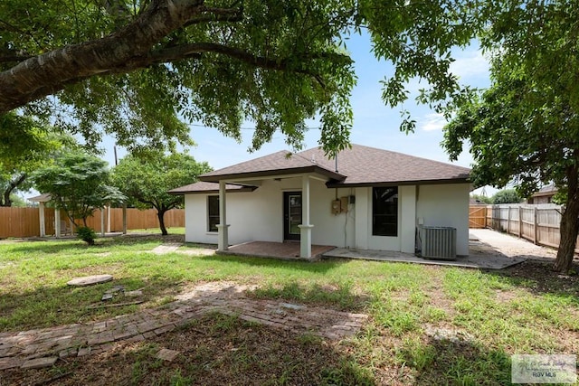 rear view of property with cooling unit, a patio area, and a lawn