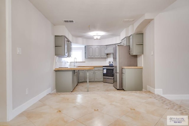 kitchen with custom exhaust hood, stainless steel appliances, sink, light tile patterned floors, and gray cabinets