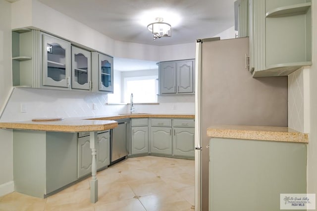 kitchen with stainless steel dishwasher, sink, gray cabinetry, and backsplash