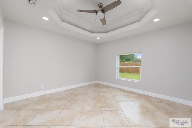 tiled spare room featuring a raised ceiling and ceiling fan