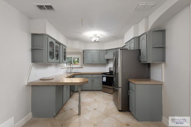 kitchen with sink, stainless steel appliances, kitchen peninsula, gray cabinets, and light tile patterned flooring