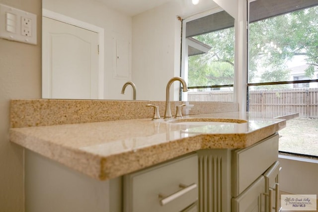 kitchen featuring cream cabinets, light stone counters, and sink