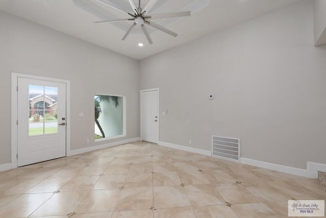 unfurnished room featuring ceiling fan and a towering ceiling