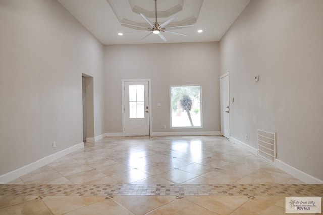 interior space featuring a towering ceiling, a raised ceiling, ceiling fan, and crown molding