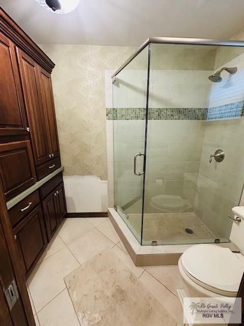 bathroom featuring tile patterned floors, a shower with door, and toilet