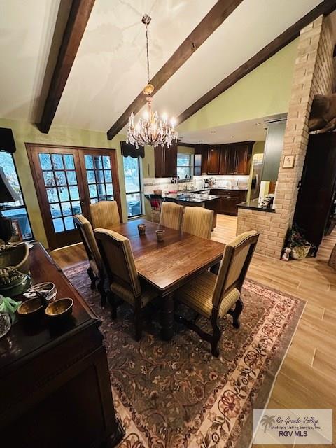 dining space featuring an inviting chandelier, beam ceiling, high vaulted ceiling, and light wood-type flooring