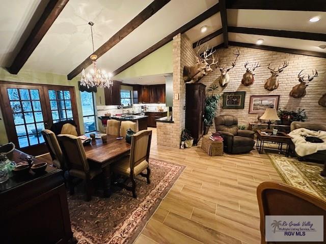 dining area featuring brick wall, beam ceiling, and a notable chandelier