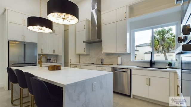 60 Jacklyn St, Rancho Viejo, TX 78575 - kitchen with appliances with stainless steel finishes, sink, wall chimney range hood, a center island with sink, and white cabinets