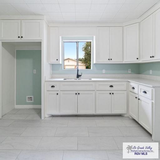 1802 High St, Harlingen, TX 78550 - kitchen featuring white cabinetry, sink, and light tile patterned floors