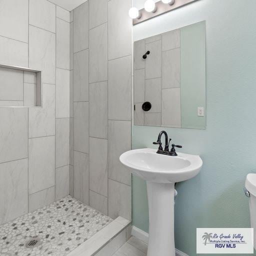 bathroom with toilet and a tile shower