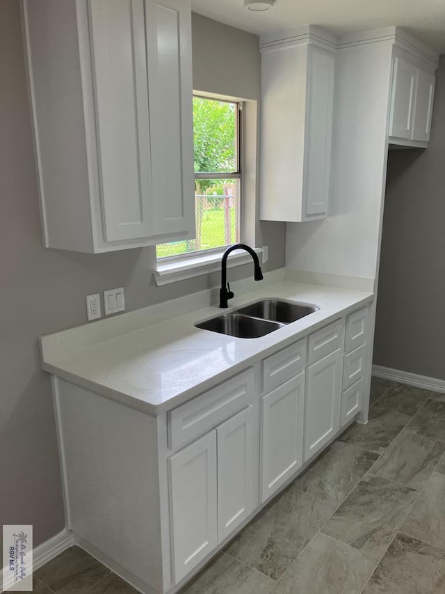 902 Rio Hondo Rd, Harlingen, TX 78550 - kitchen featuring a sink, white cabinetry, light countertops, and baseboards