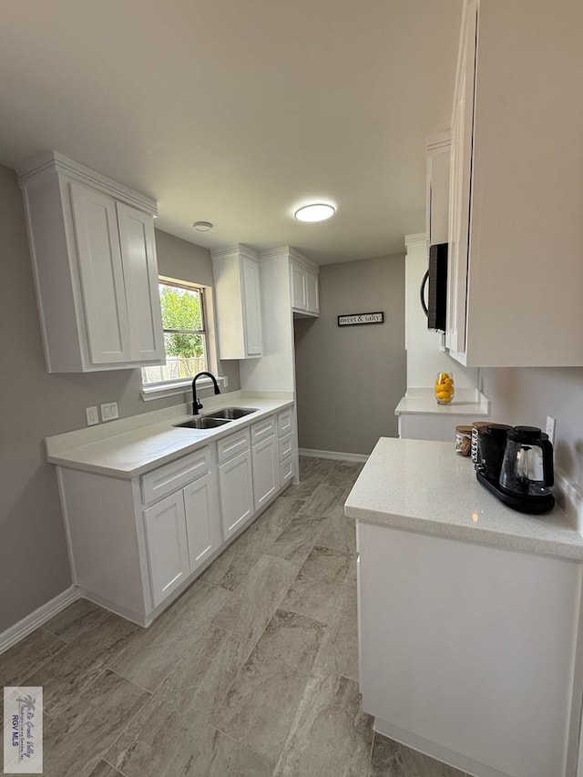 902 Rio Hondo Rd, Harlingen, TX 78550 - kitchen with a sink, white cabinets, baseboards, and light countertops