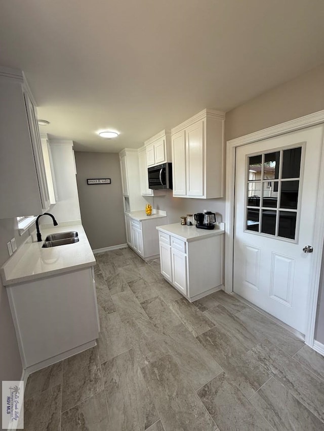 902 Rio Hondo Rd, Harlingen, TX 78550 - kitchen with stainless steel microwave, a sink, light countertops, and white cabinetry