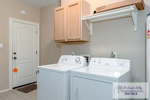 washroom featuring cabinets, light tile patterned floors, and washing machine and clothes dryer