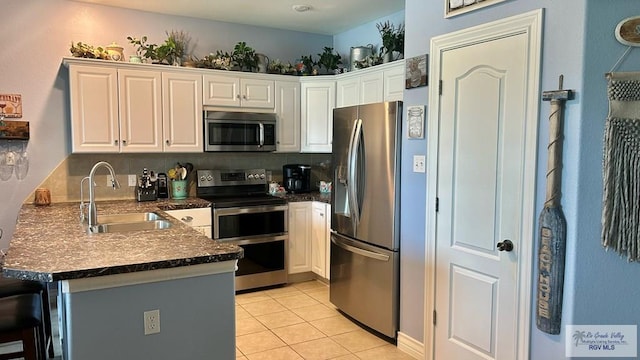 kitchen with kitchen peninsula, tasteful backsplash, stainless steel appliances, sink, and white cabinets