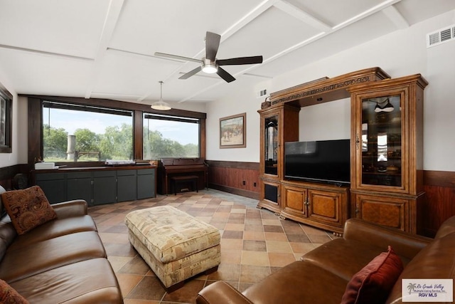 living room featuring ceiling fan and wood walls