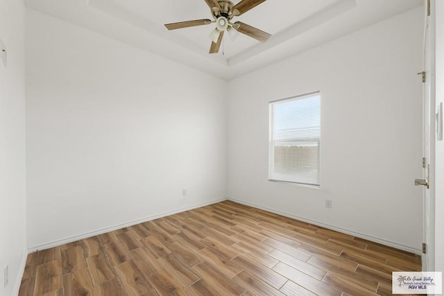 spare room featuring hardwood / wood-style floors, a raised ceiling, and ceiling fan