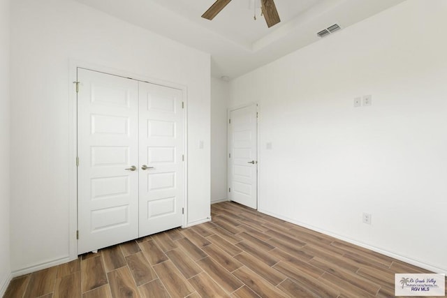 unfurnished bedroom with ceiling fan, a closet, and wood-type flooring