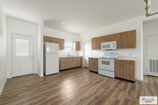 kitchen featuring dark hardwood / wood-style flooring, white appliances, and sink