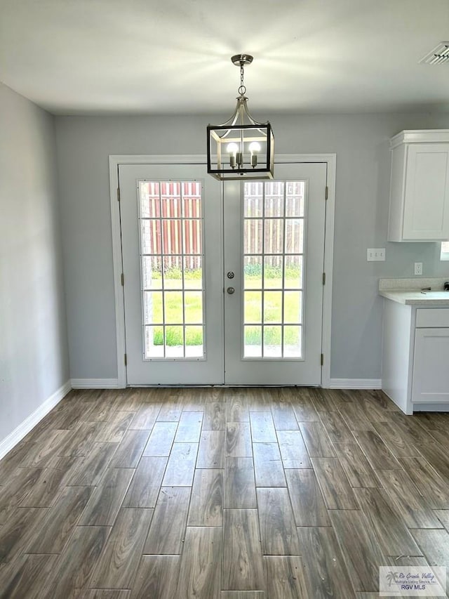 doorway to outside featuring visible vents, baseboards, an inviting chandelier, and dark wood-style floors