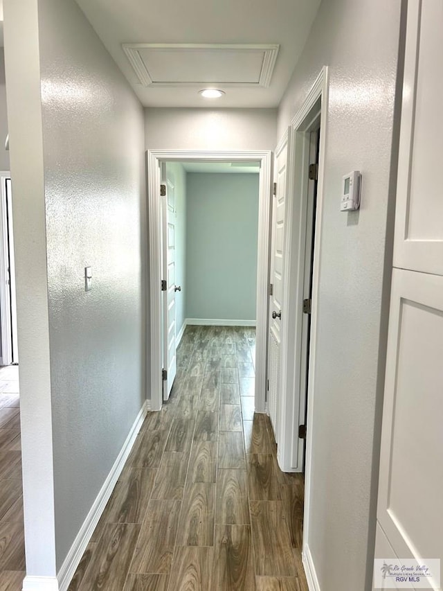 corridor with dark wood-type flooring, attic access, and baseboards